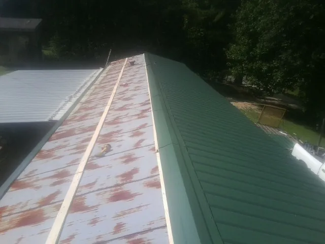 Old rusted panels beside newly installed green metal roofing — Wind Damage Roof Repair by Roofing Brothers in Jonestown