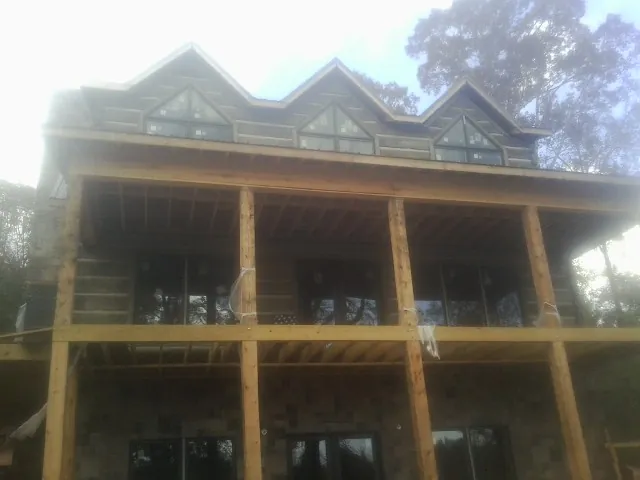 Dormers and porch framing on a large log home under construction — Roof Coating work by our crew in Jonestown
