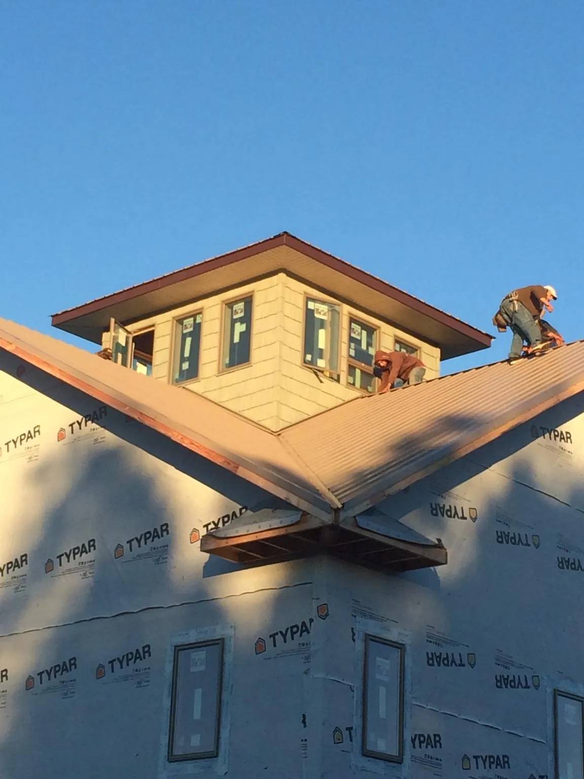 Roofers working around a rooftop cupola on a new metal roof at sunset — Roof Waterproofing in Jonestown by Roofing Brothers